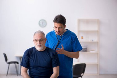 Yaşlı adam genç erkek doktoru ziyaret ediyor.
