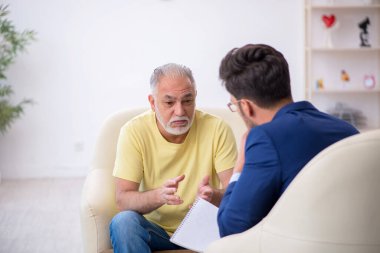 Yaşlı adam genç erkek psikoterapisti ziyaret ediyor.