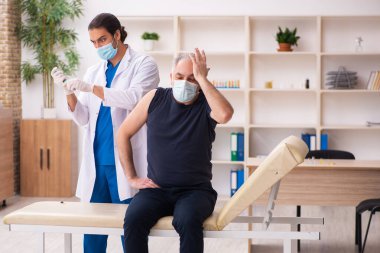Yaşlı adam covid-19 aşı konseptinde genç doktoru ziyaret ediyor.