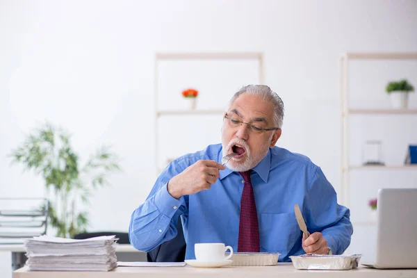 在办公室吃早餐的老男性员工 — 图库照片
