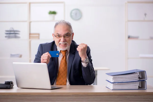 Viejo empleado con tarjeta de crédito en la oficina —  Fotos de Stock