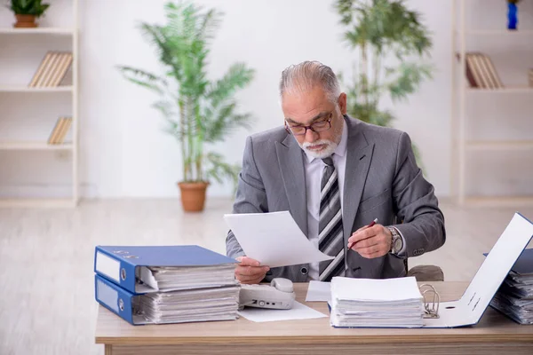 Velho empregado masculino e muito trabalho no escritório — Fotografia de Stock