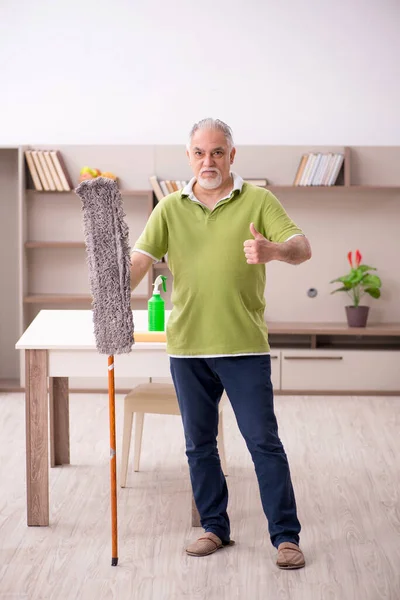 Oude man die het huis schoonmaakt — Stockfoto