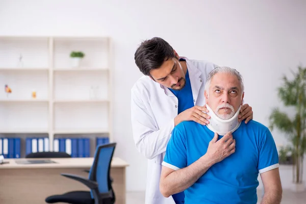 Vecchio collo ferito paziente maschile in visita giovane medico maschile — Foto Stock