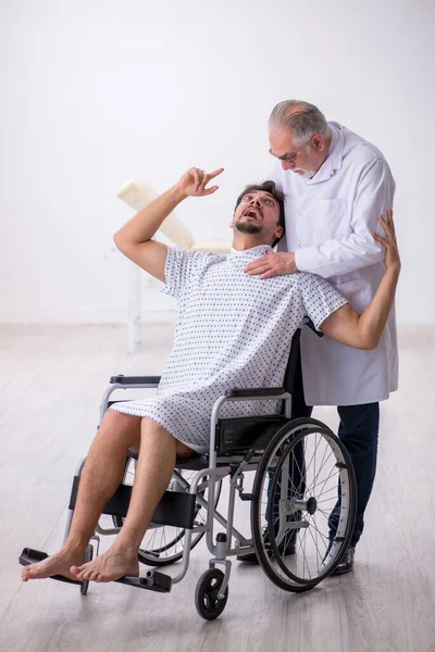 Old male doctor psychiatrist examining young disabled patient