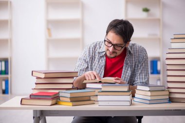 Genç bir erkek öğrenci ve sınıfta çok fazla kitap var.