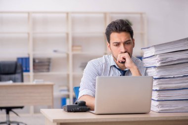 Genç bir erkek çalışan ve ofiste çok fazla iş var.