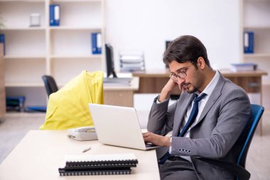 Genç erkek çalışan işyerinde yeni doğan çocuğa bakıyor.