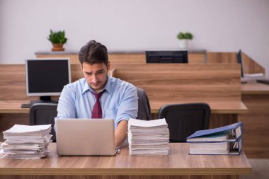 Ofisteki aşırı işten memnun olmayan genç bir erkek işçi.