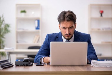 Ofisteki aşırı işten memnun olmayan genç bir erkek işçi.