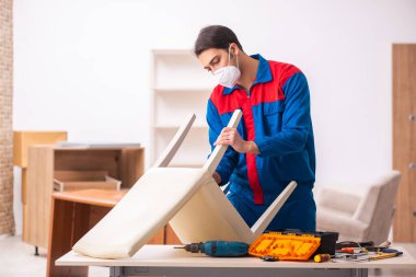 Genç erkek marangoz salgın sırasında ofiste çalışıyor.