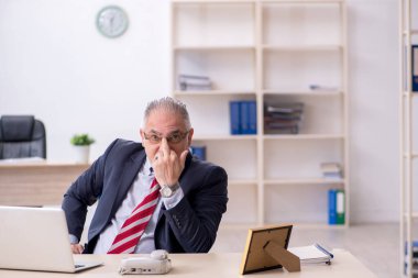 Ofiste çalışan yaşlı bir erkek.