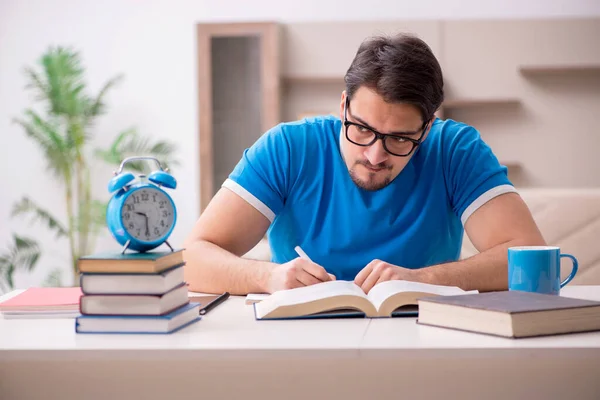Joven estudiante masculino que estudia en casa en concepto de gestión del tiempo — Foto de Stock
