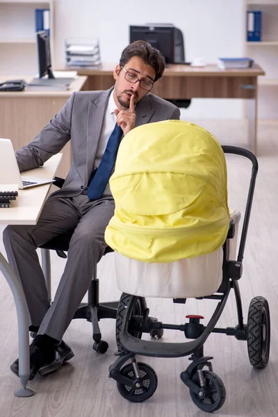 Joven empleado masculino que cuida a recién nacido en el lugar de trabajo — Foto de Stock