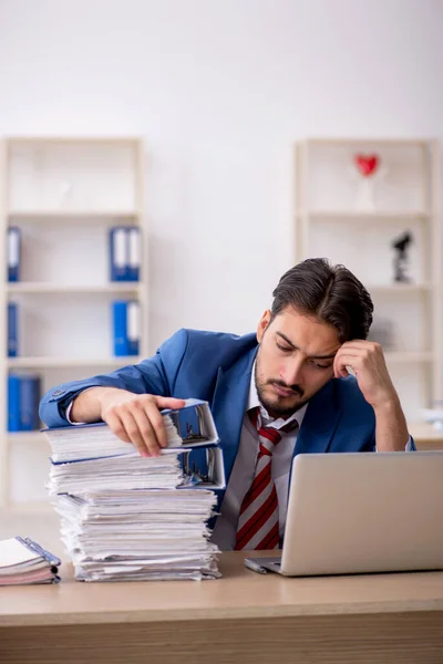 Jovem funcionário masculino e muito trabalho no escritório — Fotografia de Stock