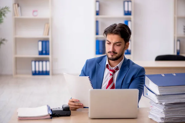 Joven empleado masculino y demasiado trabajo en la oficina —  Fotos de Stock