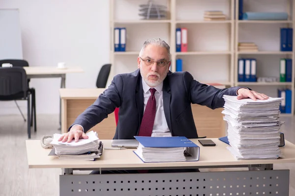 Oudere mannelijke werknemer en te veel werk op het werk — Stockfoto