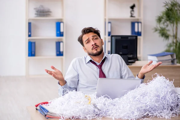 Jeune employé masculin et beaucoup de papiers coupés dans le bureau — Photo