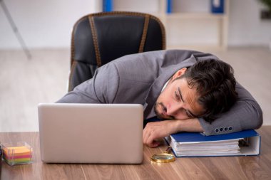 Genç erkek çalışan ofiste oturuyor.