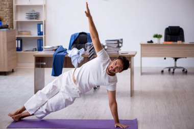 Genç erkek çalışan ofiste spor egzersizleri yapıyor.