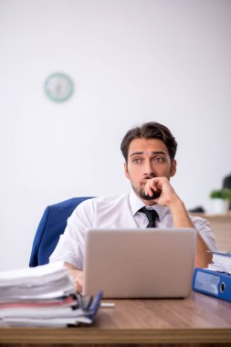 Genç bir erkek çalışan ve ofiste çok fazla iş var.