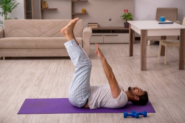 Genç adam evde spor yapıyor.