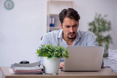 Ofisteki aşırı işten memnun olmayan genç bir erkek işçi.