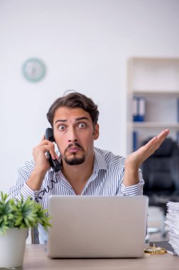 Ofisteki aşırı işten memnun olmayan genç bir erkek işçi.