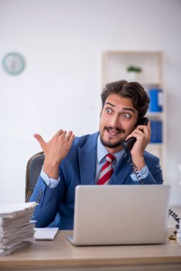 Genç bir erkek çalışan ve ofiste çok fazla iş var.