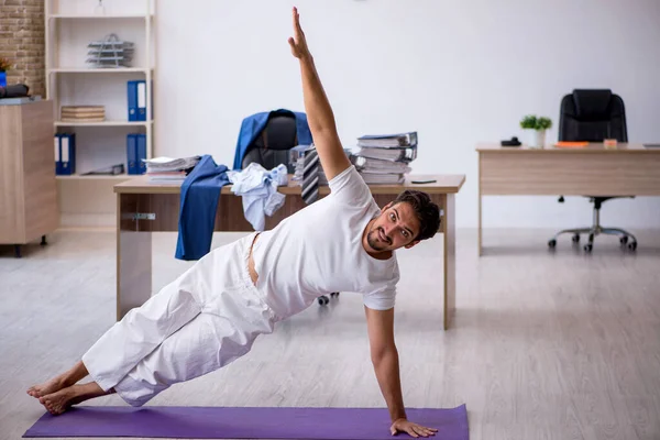 Genç erkek çalışan ofiste spor egzersizleri yapıyor.