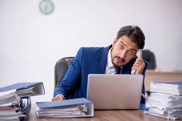 Jovem funcionário masculino e muito trabalho no escritório — Fotografia de Stock