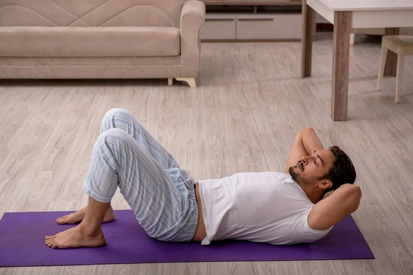 Genç adam evde spor yapıyor.