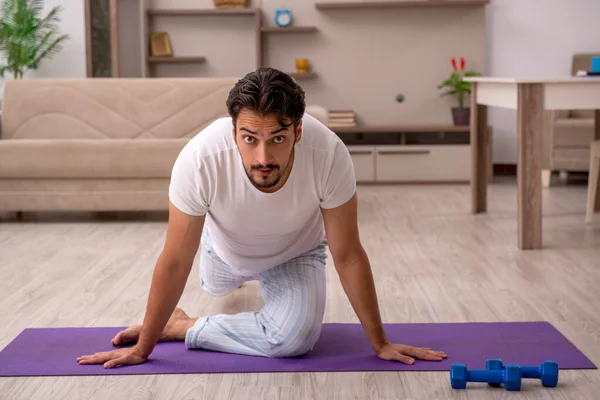 Giovane uomo che fa esercizi sportivi a casa — Foto Stock