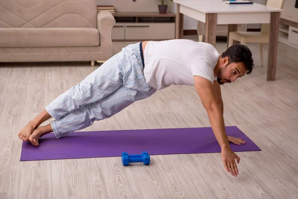 Genç adam evde spor yapıyor.