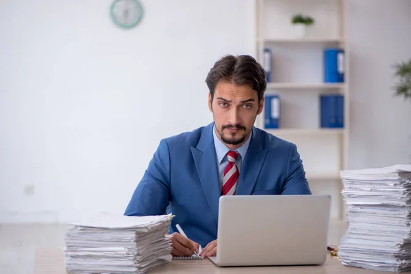 Joven empleado masculino y demasiado trabajo en la oficina — Foto de Stock