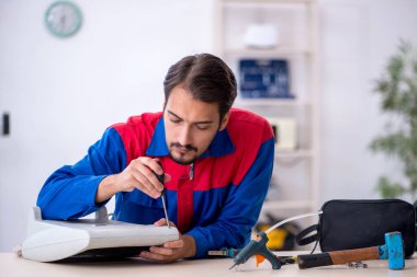 Genç erkek tamirci ısıtıcıyı tamir ediyor.