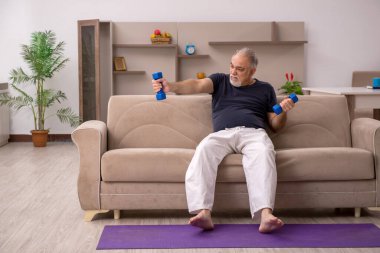 Yaşlı adam evde spor yapıyor.