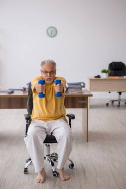 Ofiste spor egzersizleri yapan eski bir işadamı.