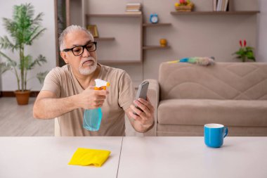 Yaşlı adam evde ev işi yapıyor.