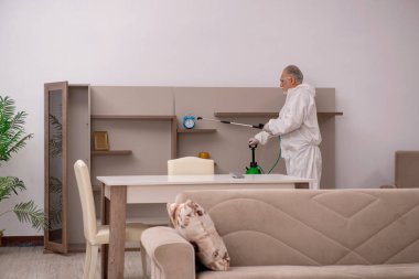 Yaşlı erkek müteahhit evde haşere kontrolü yapıyor.