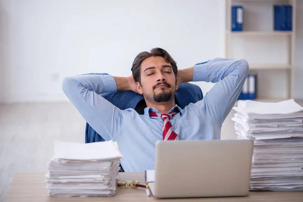 Joven empleado masculino y demasiado trabajo en la oficina —  Fotos de Stock