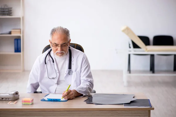 Old male doctor working in the clinic — Stock Photo, Image