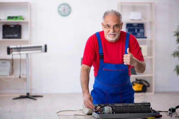 Reparador antigo reparando ar-condicionado na oficina — Fotografia de Stock