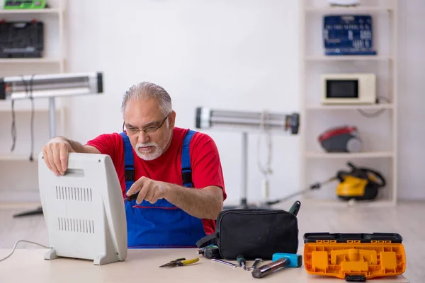 Old repairman repairing heater at workshop — Stock Photo, Image