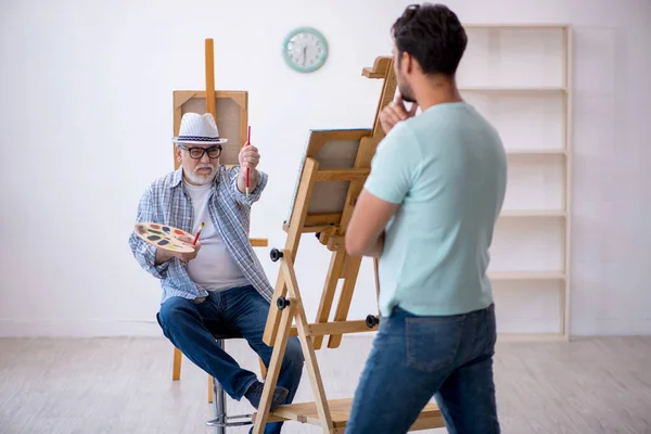 Old painter and young male model at the studio — Stock Photo, Image