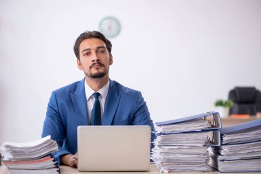 Genç bir erkek çalışan ve ofiste çok fazla iş var.