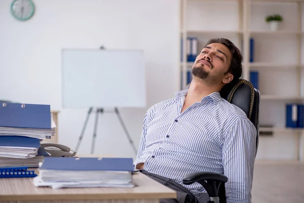 Jovem funcionário masculino e muito trabalho no escritório — Fotografia de Stock