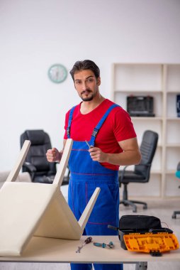 Genç erkek marangoz atölyede çalışıyor.