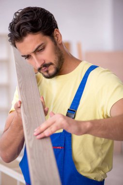 Genç erkek marangoz atölyede çalışıyor.