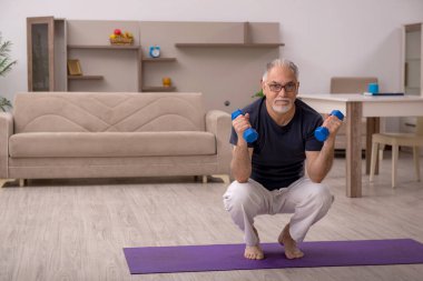 Yaşlı adam evde spor yapıyor.